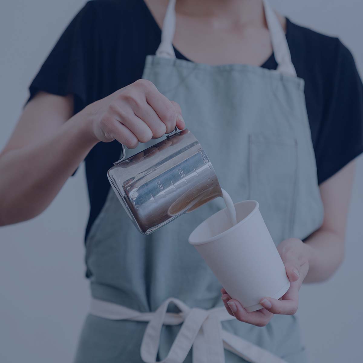 Person pouring milk into coffee cup